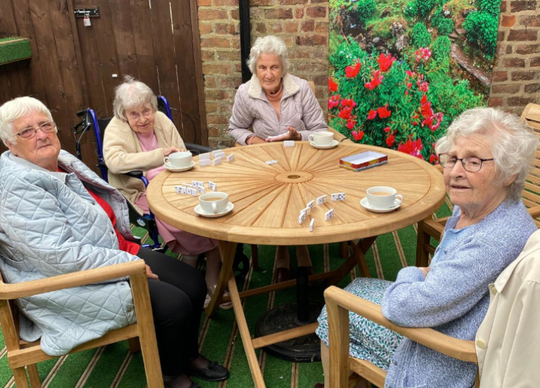Friends playing dominoes in the garden at our Happy Days day centre