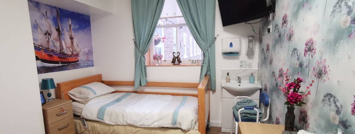 A bright single bedroom at Shetland House with en-suite wash area
